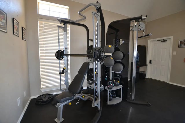 Gym equipment with weights and exercise bench gym room at The Oaks of Arlington in Arlington Student Accommodation