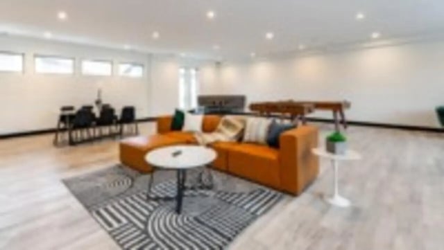Orange sofa black chairs and tables living room at Victory at Burcham Place in East Lansing Student Accommodation