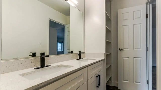 Double vanity with modern faucets and built-in shelving bathroom at Victory at Burcham Place in East Lansing Student Accommodation