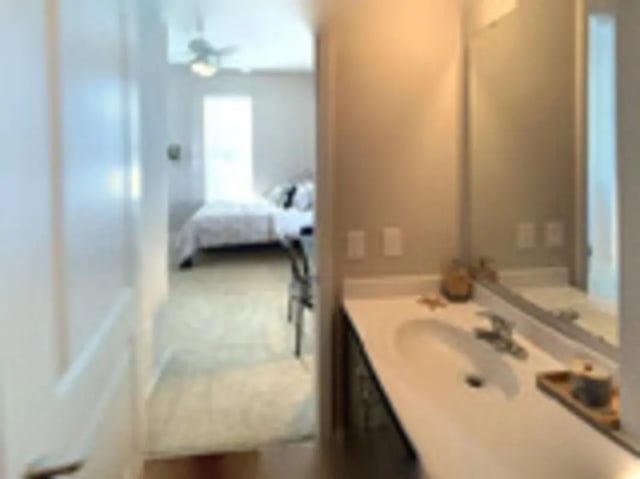 Sink and mirror in bathroom with bed beyond bedroom at The Nest at 4955 in Wilmington Student Accommodation