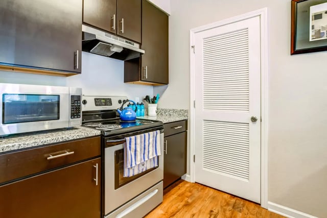 Microwave stove dark cabinets white door kitchen at The Nest at 4955 in Wilmington Student Accommodation