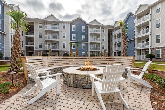 Fire pit with chairs and apartment buildings exterior at The Nest at 4955 in Wilmington Student Accommodation