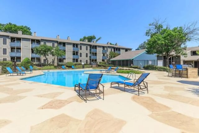 Blue lounge chairs surround a pool exterior at Villas at Alameda in Fort Worth Student Accommodation