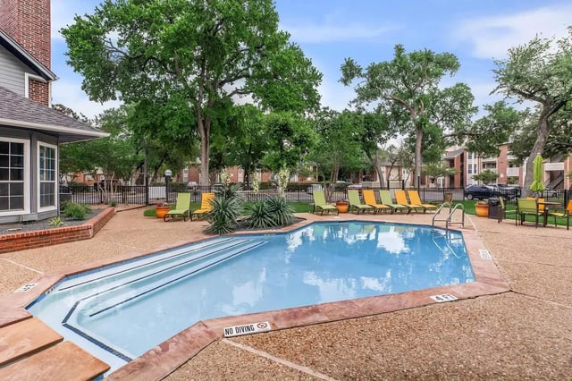 Pool with lounge chairs and trees exterior at Villas at Shadow Oaks in Austin Student Accommodation