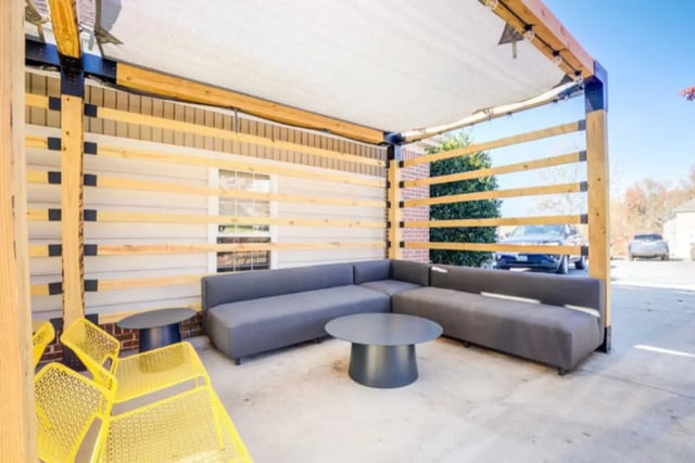 Sectional sofa tables yellow chairs outdoor living area at Collegiate Suites of Blacksburg in Blacksburg Student Accommodation