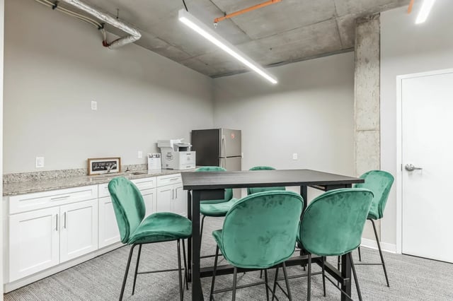 Table with green chairs refrigerator and cabinets common area at The Ross Salisbury in Salisbury Student Accommodation