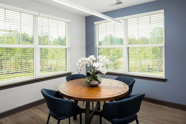 Wooden table chairs flower plant windows common area at Avoca in Louisville Student Accommodation