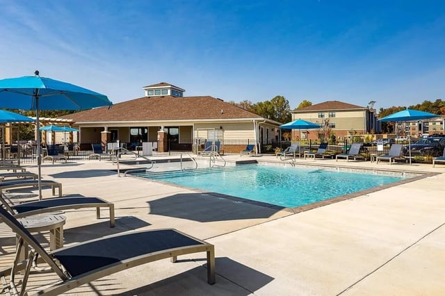Pool with lounge chairs and blue umbrellas exterior at Avoca in Louisville Student Accommodation