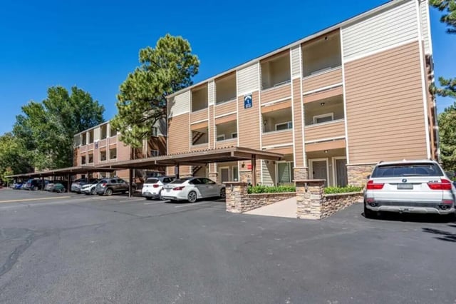 Apartment building with covered parking and cars exterior at The Commons at Sawmill in Flagstaff Student Accommodation