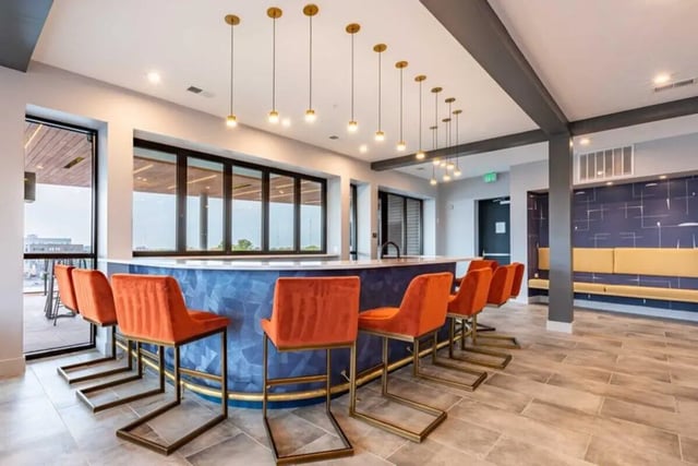 Orange bar stools blue counter modern lighting living area at 8th and High Columbus in Columbus Student Accommodation