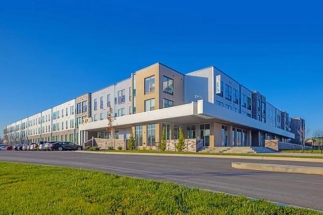 Modern multi story building with parked cars exterior at Proxi Lawrence in Lawrence Student Accommodation