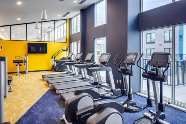 Treadmills ellipticals and TVs fitness center room at Proxi Lawrence in Lawrence Student Accommodation