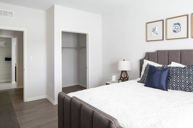 Bed with navy pillows and open closet bedroom at Frontgate in Louisville Student Accommodation