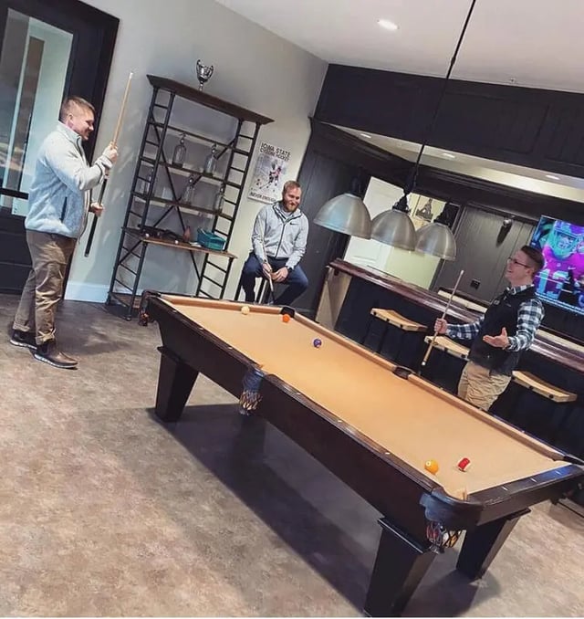 Men playing pool near shelves and bar living room at Copper Beech at Ames in Ames Student Accommodation