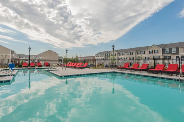 Red lounge chairs line student accommodation pool exterior at Copper Beech at Ames in Ames Student Accommodation