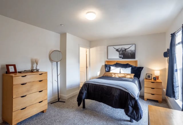 Wood dresser round mirror bed with artwork bedroom at Copper Beech at Ames in Ames Student Accommodation