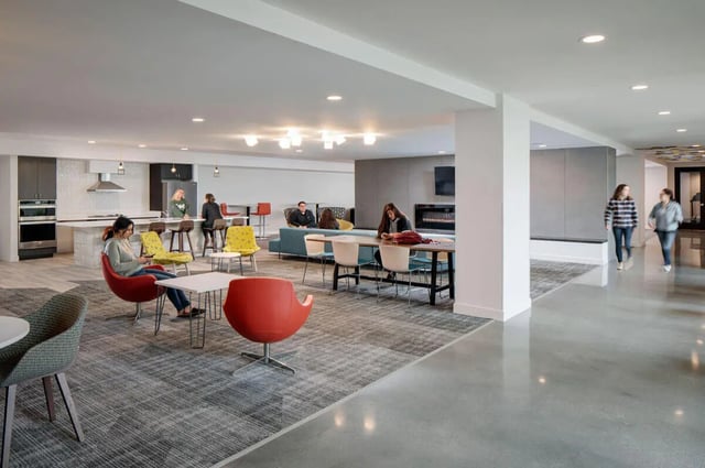 Students seated at kitchen counter and lounge area living room at M @ College in San Diego Student Accommodation