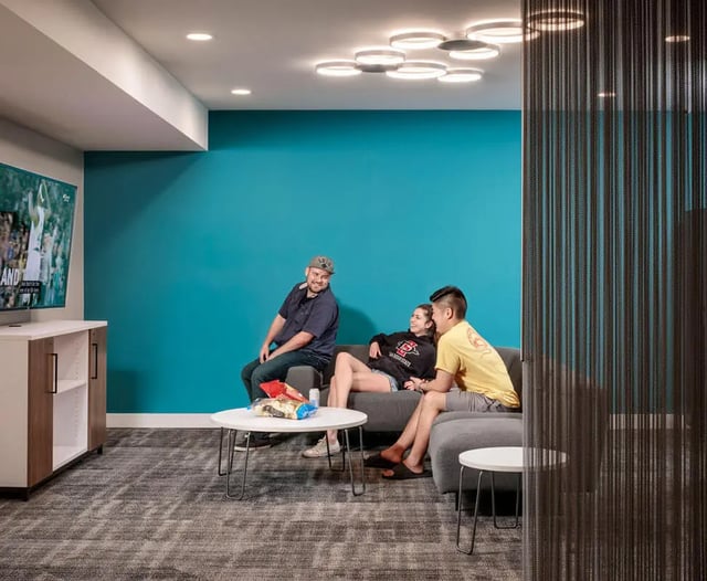 Students watching TV on couch living room at M @ College in San Diego Student Accommodation