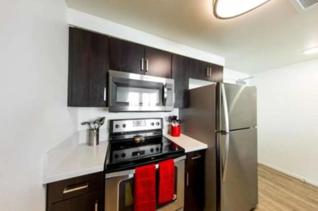 Stainless steel appliances dark cabinets red towels kitchen at Prisma in San Diego Student Accommodation