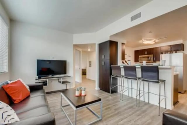 Sofa TV coffee table bar stools kitchen living room at Prisma in San Diego Student Accommodation