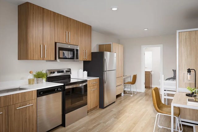 Kitchen with stainless steel appliances desks and bed at The Cove in Goleta Student Accommodation