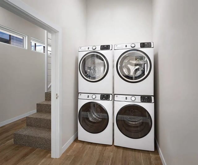 Stacked washers and dryers next to stairs Laundry room at The Cove in Goleta Student Accommodation