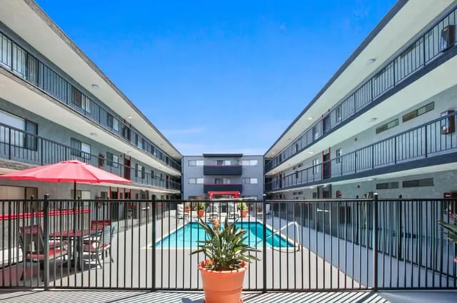 Courtyard with pool patio furniture and buildings exterior at Valleywood in Los Angeles Student Accommodation