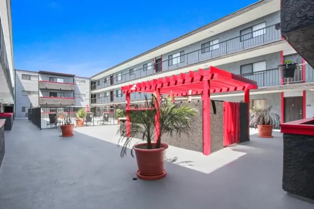 Courtyard with potted plants and red pergola exterior at Valleywood in Los Angeles Student Accommodation