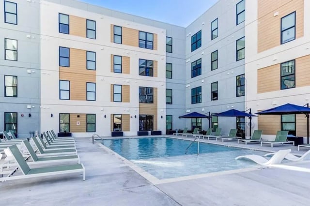 Pool lounge chairs umbrellas exterior building exterior at The Helmsman in Savannah Student Accommodation