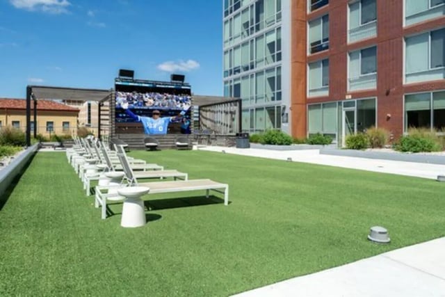 Lounge chairs on lawn with large outdoor screen exterior at Everly On The Loop in St. Louis Student Accommodation