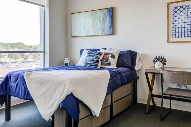 Bed with blue bedding white throw desk chair bedroom at Everly On The Loop in St. Louis Student Accommodation