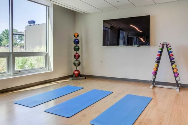 Yoga mats dumbbells weights television fitness room at Everly On The Loop in St. Louis Student Accommodation