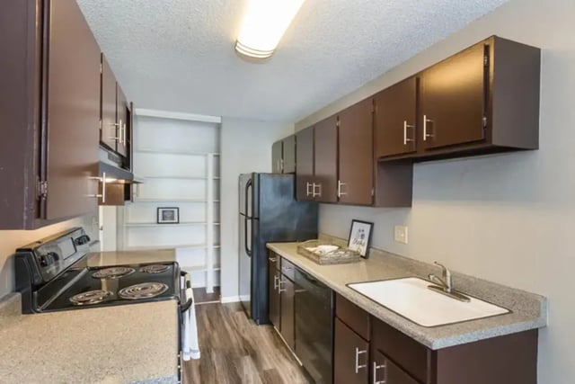 Dark brown cabinets sink stove and refrigerator kitchen at Aviator Apartments in Colorado Springs Student Accommodation