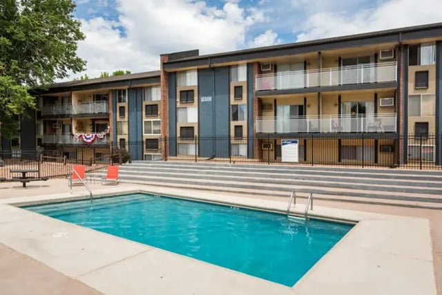Swimming pool with chairs next to apartment building exterior at Aviator Apartments in Colorado Springs Student Accommodation