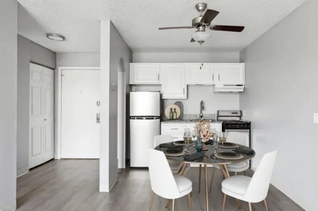 Dining table with white chairs and kitchen studio at Chestnut Springs Apartments in Colorado Springs Student Accommodation