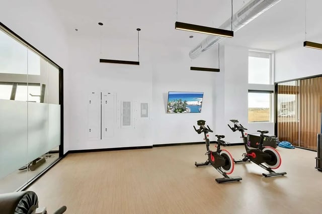 Two stationary bikes wall lockers TV playing area at Claro at High Point in Aurora Student Accommodation