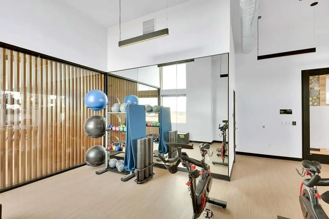 Gym with exercise balls weights bikes and mirrors playing area at Claro at High Point in Aurora Student Accommodation