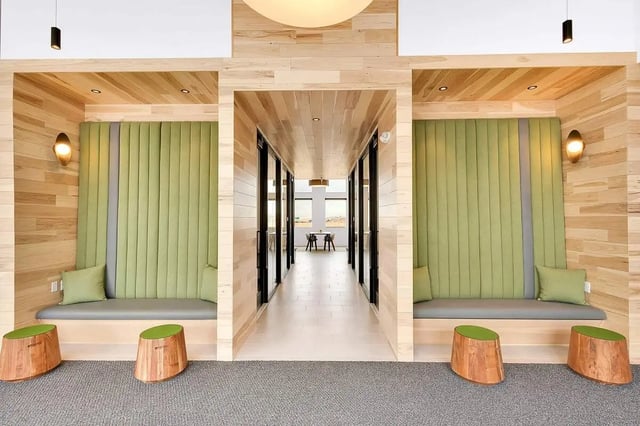 Built-in seating with green cushions and stools common area at Claro at High Point in Aurora Student Accommodation