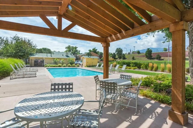 Tables chairs pool and lounge chairs outdoor living area at Copper Chase Apartments in Colorado Springs Student Accommodation