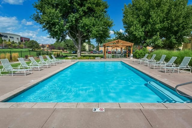 Deck chairs surround bright blue swimming pool exterior at Copper Chase Apartments in Colorado Springs Student Accommodation
