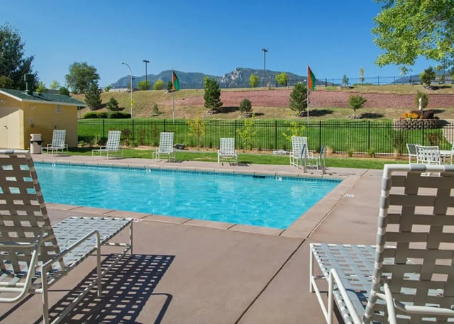 Pool with lounge chairs and mountains exterior at Copper Chase Apartments in Colorado Springs Student Accommodation