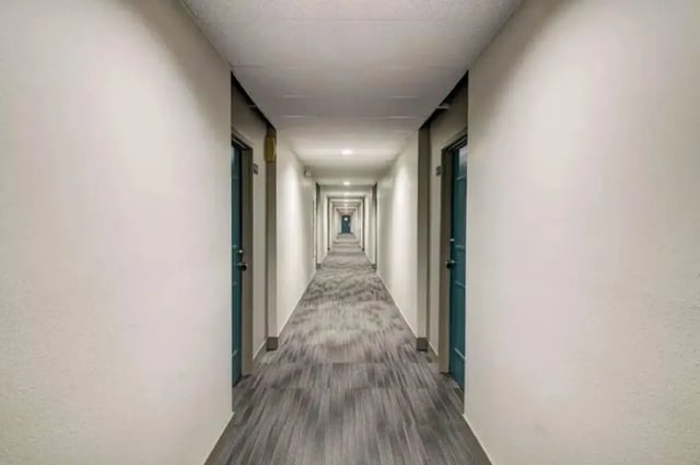 Long hallway with doors and patterned carpet hallway at Copper Chase Apartments in Colorado Springs Student Accommodation