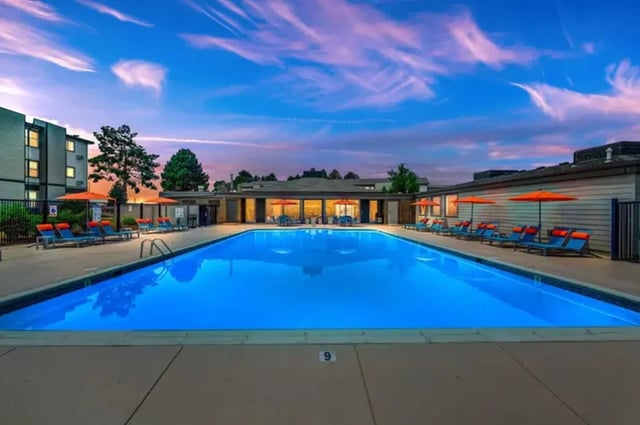 Large blue swimming pool with lounge chairs playing area exterior at Copper Chase Apartments in Colorado Springs Student Accommodation