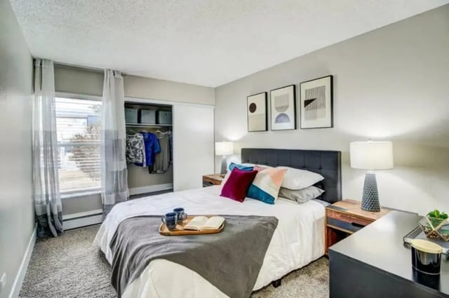 Bed with colorful pillows open book closet bedroom at Copper Chase Apartments in Colorado Springs Student Accommodation