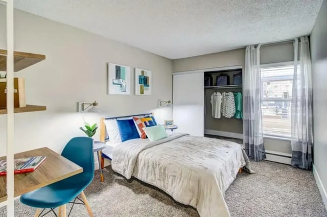 Bed desk closet with clothes and window bedroom at Copper Chase Apartments in Colorado Springs Student Accommodation