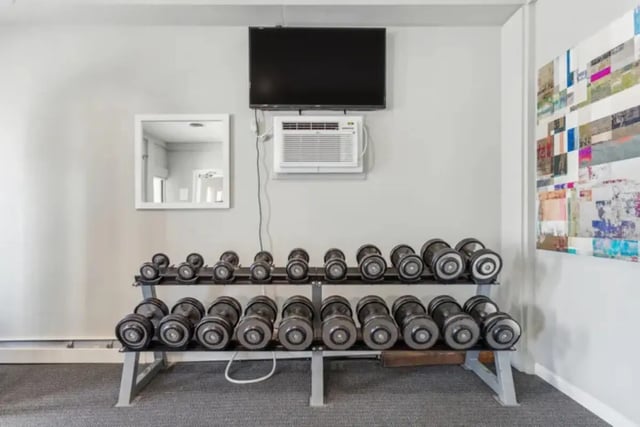 Dumbbells air conditioner TV and artwork gym area at Lincoln Springs Apartments in Colorado Springs Student Accommodation