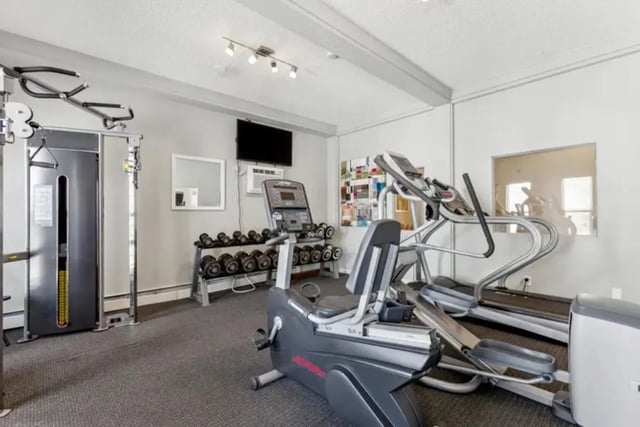 Gym equipment with dumbbells and TV playing area at Lincoln Springs Apartments in Colorado Springs Student Accommodation