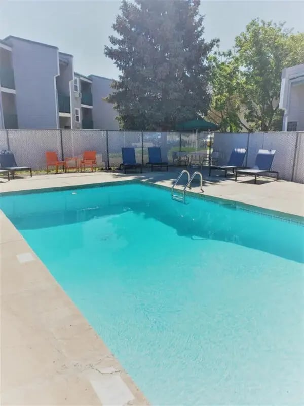 Pool with lounge chairs and umbrellas outdoor area at Lincoln Springs Apartments in Colorado Springs Student Accommodation