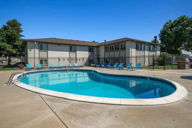 Blue lounge chairs surround outdoor swimming pool exterior at Newgate in Wheat Ridge Student Accommodation