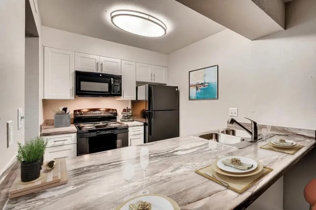 Modern kitchen with black appliances and marble island kitchen at Newgate in Wheat Ridge Student Accommodation